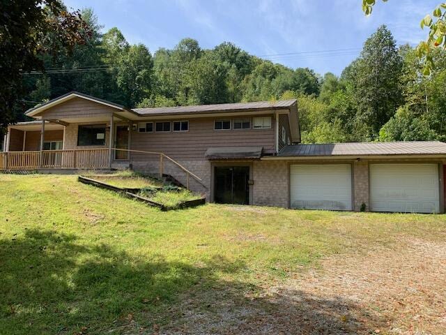 back of house featuring a lawn, a garage, and covered porch