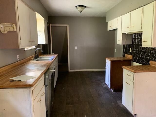 kitchen with dark hardwood / wood-style flooring, white cabinets, wood counters, and sink