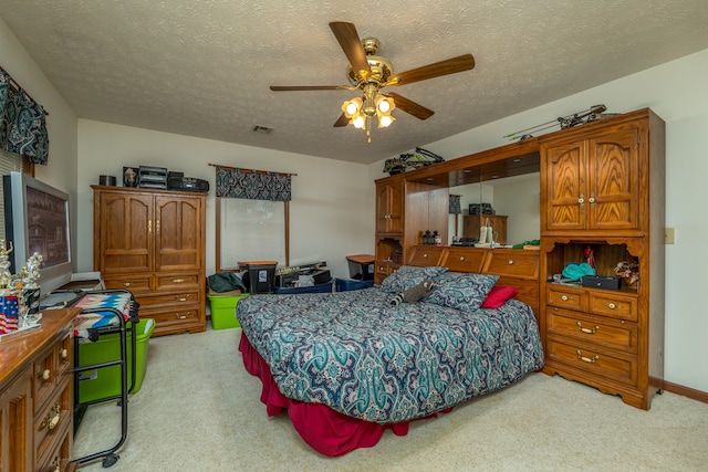 bedroom with a textured ceiling, light carpet, and ceiling fan