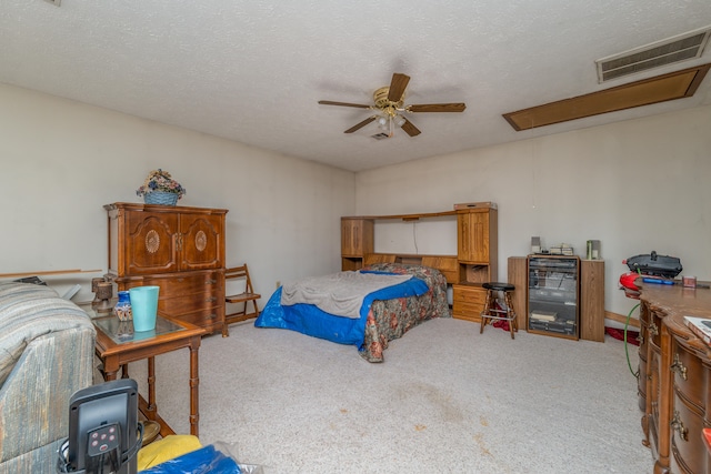 bedroom with a textured ceiling, light carpet, and ceiling fan