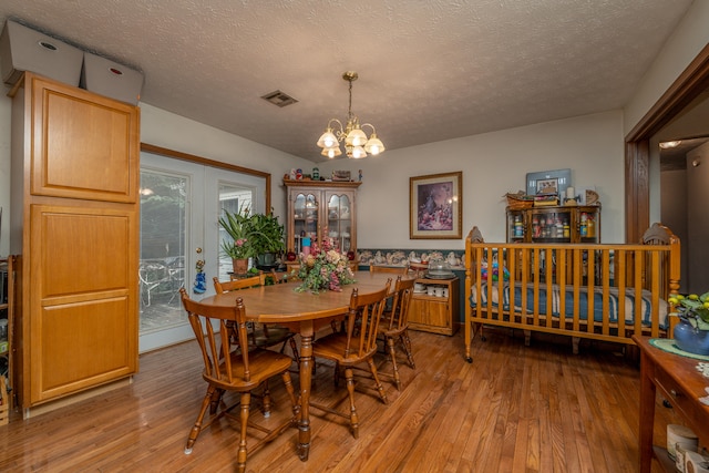 dining space featuring an inviting chandelier, a textured ceiling, and light hardwood / wood-style flooring