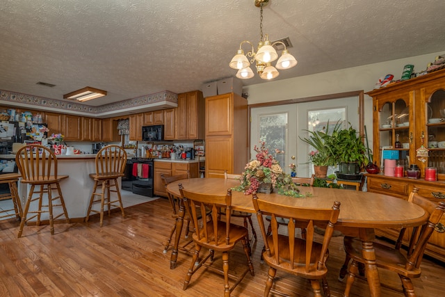 dining space with a notable chandelier, light hardwood / wood-style flooring, and a textured ceiling