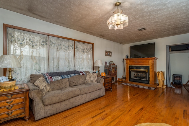 living room featuring a textured ceiling, wood-type flooring, and a chandelier