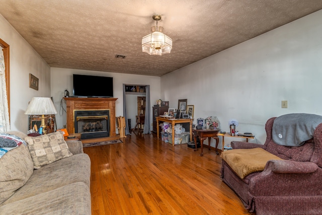 living room featuring an inviting chandelier, a textured ceiling, and hardwood / wood-style floors