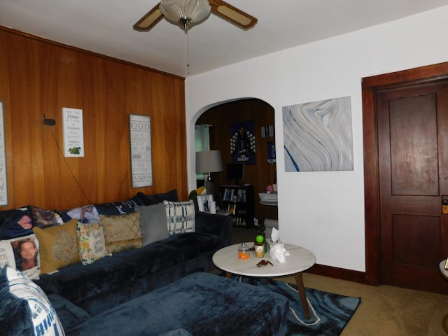 carpeted living room featuring wood walls and ceiling fan