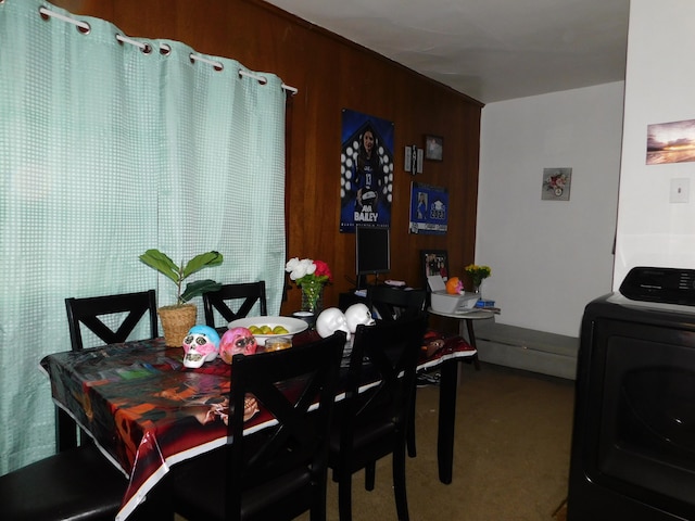 dining space featuring wooden walls, carpet, and washer / dryer