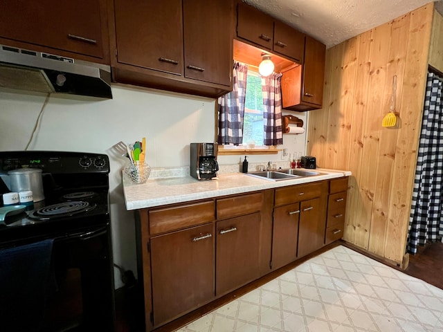 kitchen with sink, electric range, a textured ceiling, and wood walls