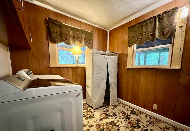 laundry area featuring a textured ceiling, wooden walls, and washing machine and clothes dryer