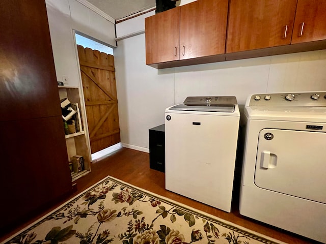 laundry area featuring independent washer and dryer, dark wood-type flooring, ornamental molding, and cabinets