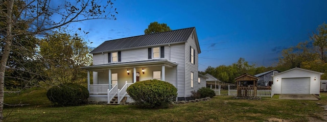 view of front of house featuring covered porch, a garage, a front lawn, and an outdoor structure