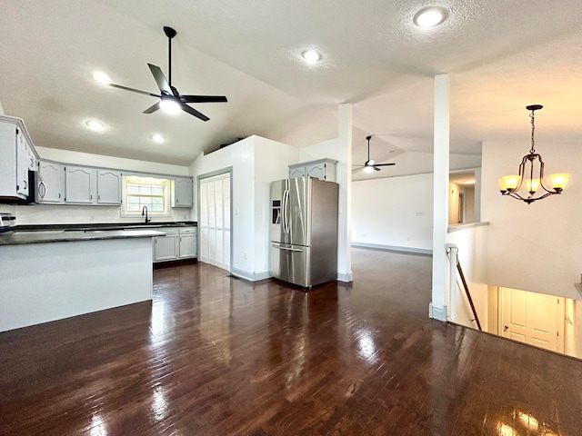 kitchen with pendant lighting, a textured ceiling, dark wood-type flooring, stainless steel appliances, and a notable chandelier