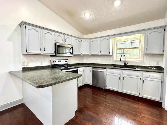 kitchen with lofted ceiling, kitchen peninsula, sink, a textured ceiling, and appliances with stainless steel finishes