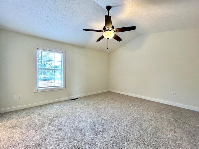 spare room featuring carpet, vaulted ceiling, a textured ceiling, and ceiling fan