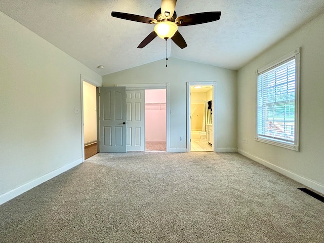 unfurnished bedroom with connected bathroom, carpet flooring, vaulted ceiling, and ceiling fan