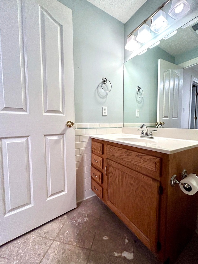 bathroom with vanity, tile walls, tile patterned flooring, and a textured ceiling