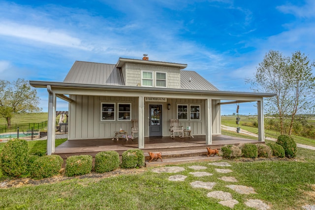 back of property featuring a lawn, a swimming pool, and covered porch