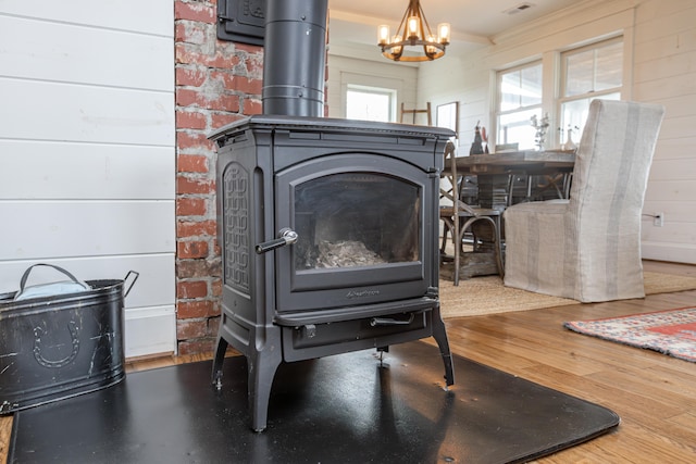 room details with ornamental molding, a wood stove, wood-type flooring, wooden walls, and a chandelier