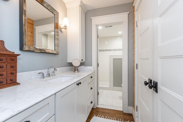 bathroom featuring a tile shower, hardwood / wood-style floors, and vanity