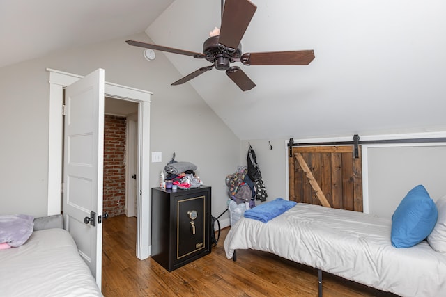 bedroom with ceiling fan, hardwood / wood-style flooring, lofted ceiling, and a barn door