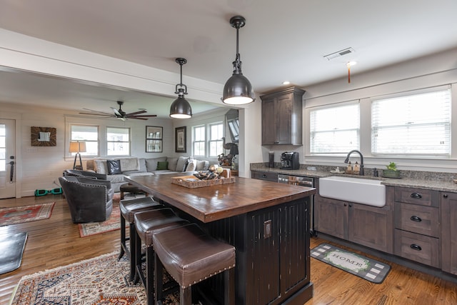 kitchen featuring a kitchen island, pendant lighting, light wood-type flooring, a kitchen bar, and ceiling fan