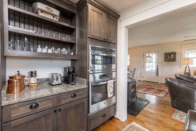 kitchen featuring dark brown cabinetry, light stone countertops, and light hardwood / wood-style flooring