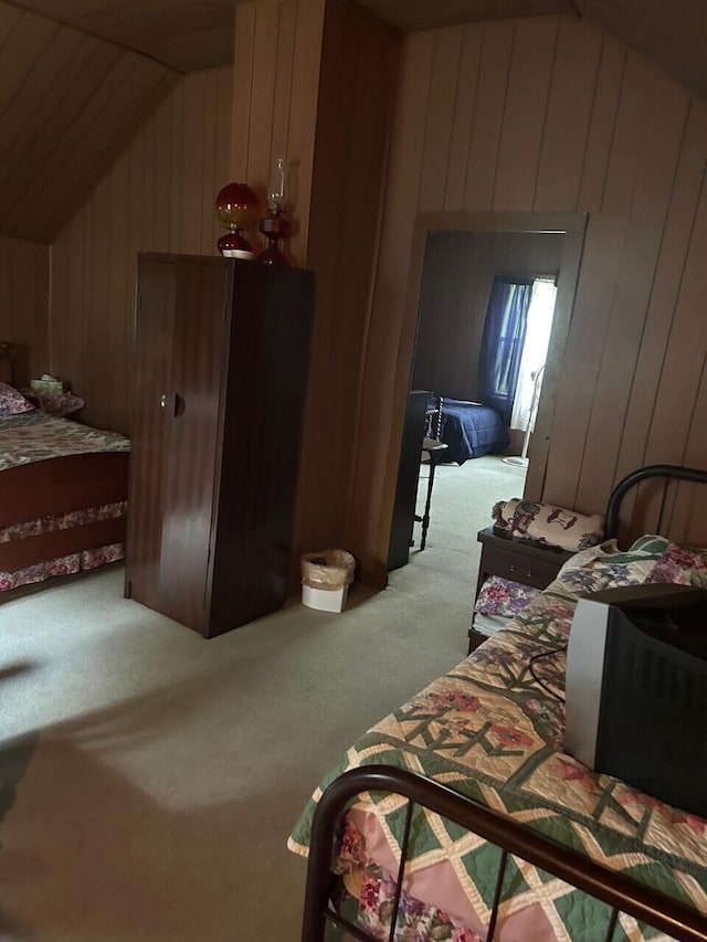 carpeted bedroom with lofted ceiling and wood walls