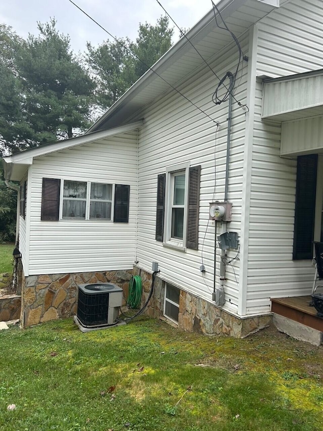 view of side of home with a lawn and central AC