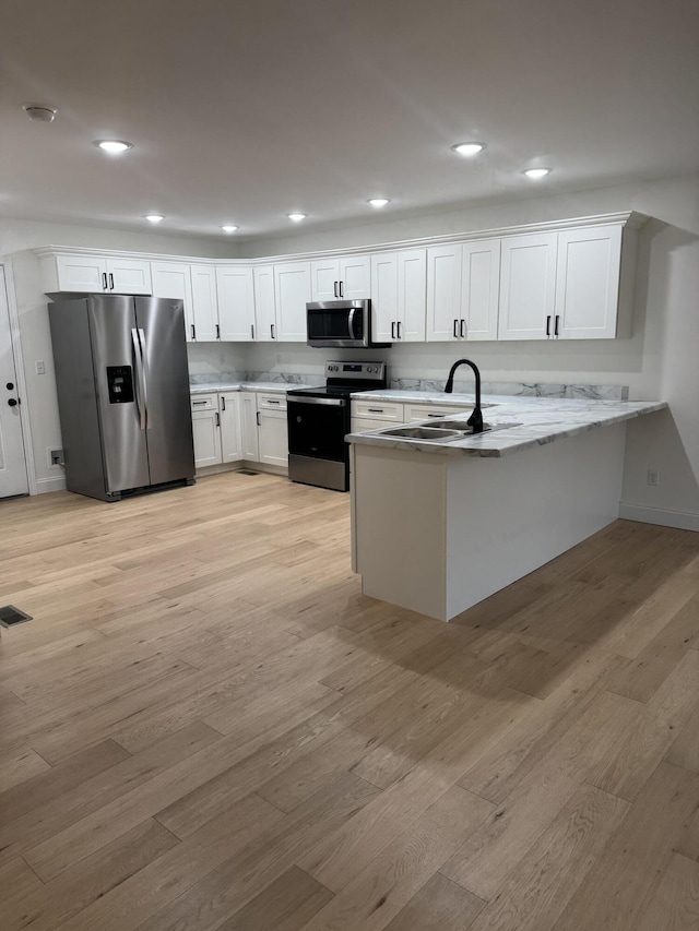 kitchen with kitchen peninsula, stainless steel appliances, light hardwood / wood-style flooring, and white cabinets