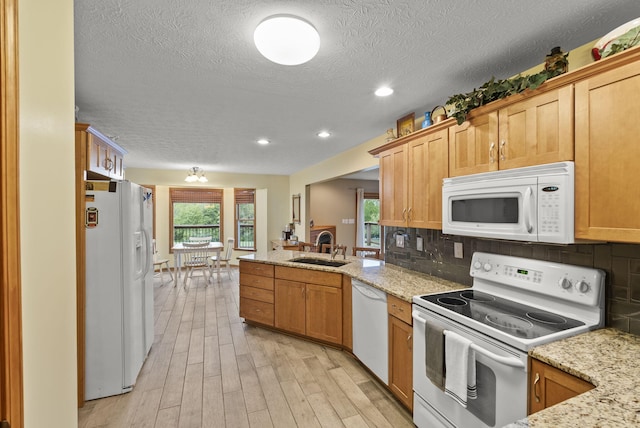 kitchen with backsplash, white appliances, light stone countertops, light wood-type flooring, and sink