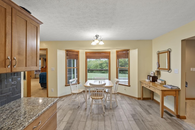 dining room featuring a textured ceiling, light wood-type flooring, and a chandelier