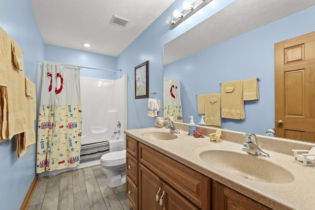 full bathroom with wood-type flooring, a textured ceiling, shower / tub combo, vanity, and toilet