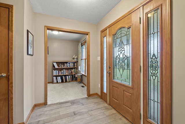 entryway with a textured ceiling and light hardwood / wood-style floors