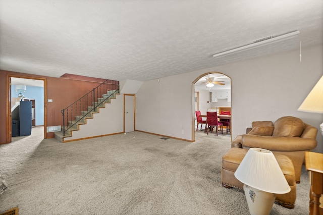 carpeted living room featuring ceiling fan and a textured ceiling