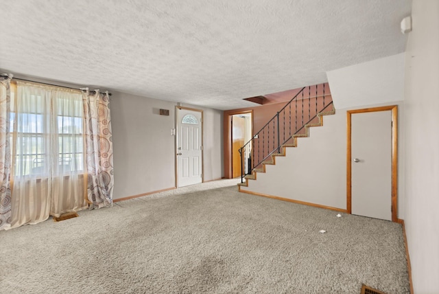 foyer entrance featuring a textured ceiling and carpet floors