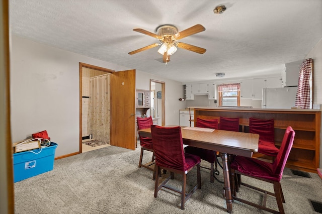 carpeted dining room with a textured ceiling and ceiling fan