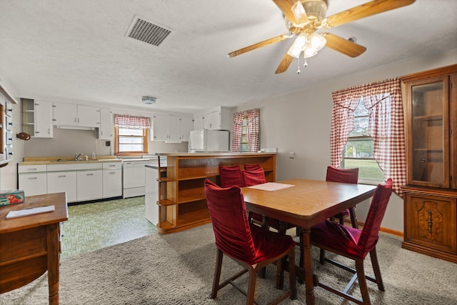 dining room featuring a textured ceiling, sink, ceiling fan, and light colored carpet