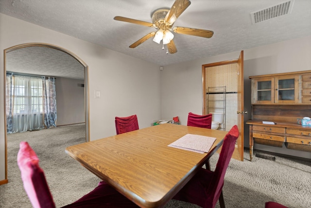 carpeted dining space with ceiling fan and a textured ceiling