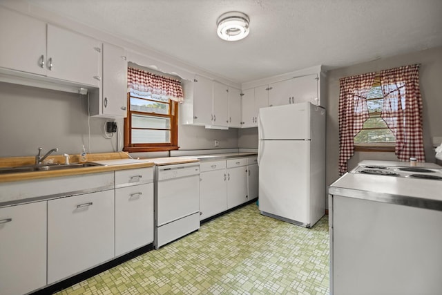 kitchen featuring white appliances, white cabinetry, and a healthy amount of sunlight