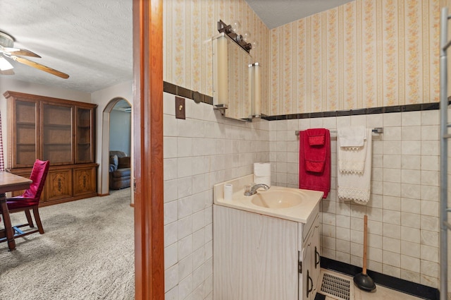 bathroom featuring ceiling fan, vanity, tile walls, and a textured ceiling