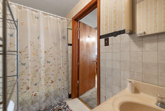 bathroom featuring tile walls, a textured ceiling, and curtained shower