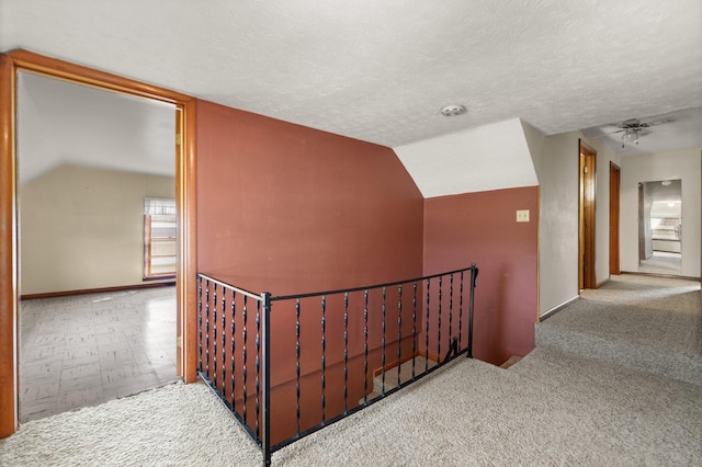 hall featuring lofted ceiling, a textured ceiling, and light colored carpet