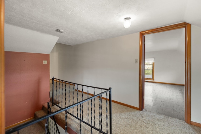 hallway with lofted ceiling and a textured ceiling