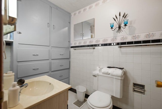 bathroom with tile walls, vanity, a textured ceiling, tile patterned flooring, and toilet