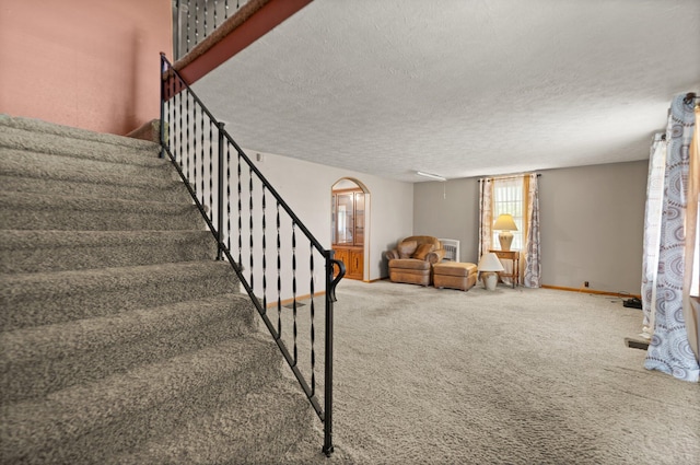 staircase featuring carpet and a textured ceiling