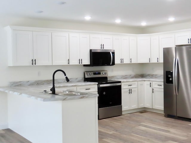 kitchen with white cabinets, appliances with stainless steel finishes, and light wood-type flooring