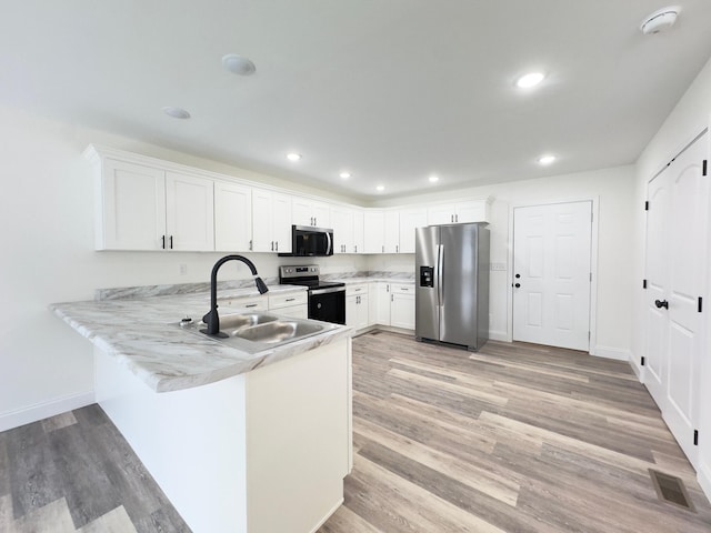 kitchen with sink, stainless steel appliances, light hardwood / wood-style flooring, kitchen peninsula, and white cabinets