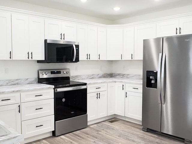 kitchen with appliances with stainless steel finishes, light wood-type flooring, white cabinetry, and light stone counters