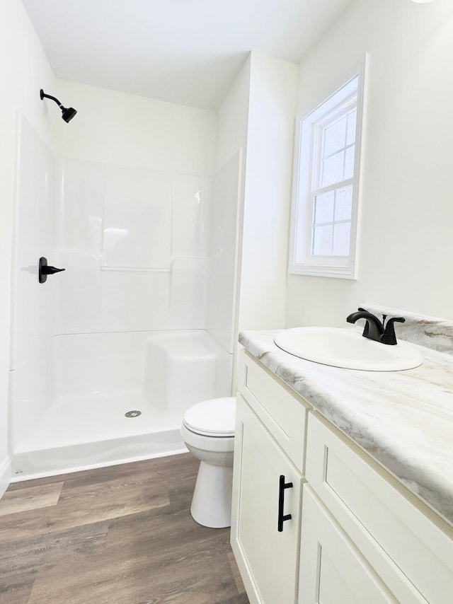 bathroom featuring a shower, toilet, vanity, and hardwood / wood-style flooring