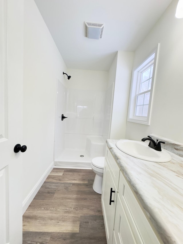 bathroom with a shower, hardwood / wood-style floors, vanity, and toilet