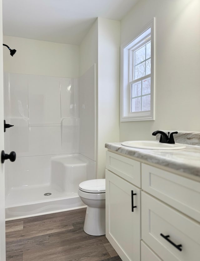 bathroom featuring vanity, toilet, wood-type flooring, and a shower